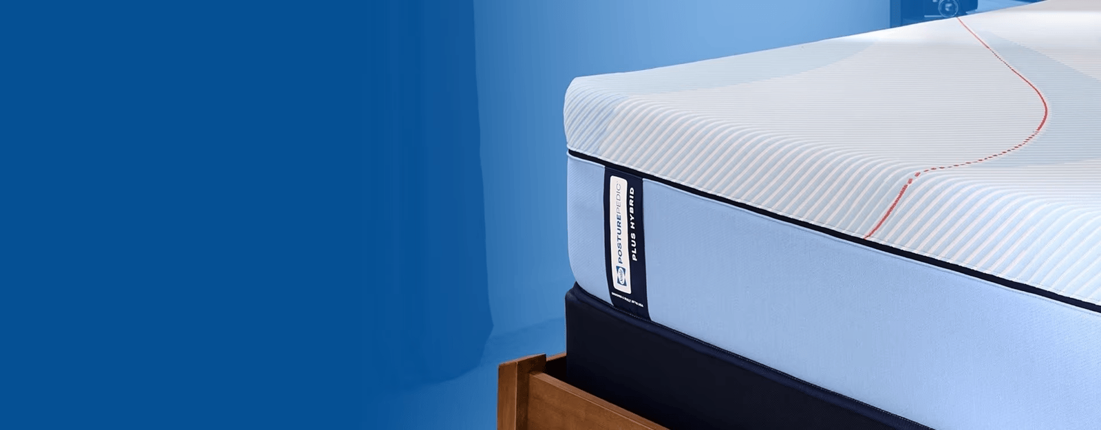 Posturepedic Plus mattress in a styled room with a blue background